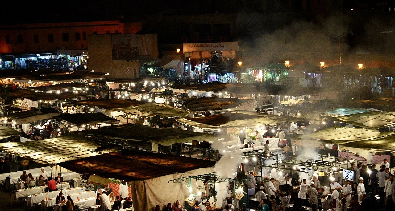 Marakeş Jemaa el-Fna çevresinde gece yemek pazarı, ışıklar ve tezgâhlar, Haziran 2026; güncel servis çizelgesi değildir.