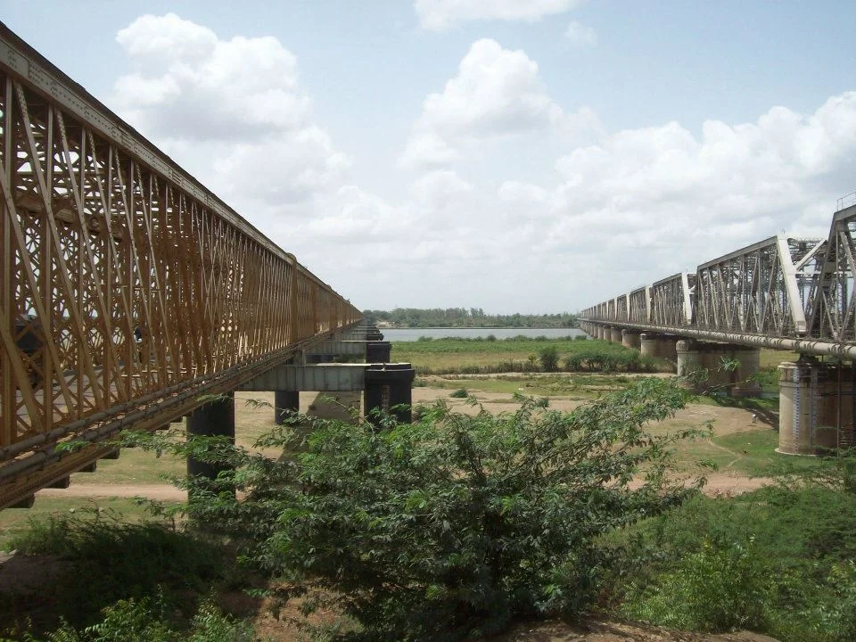 Iron truss bridge beside another bridge and a dry riverbed in Bharuch
