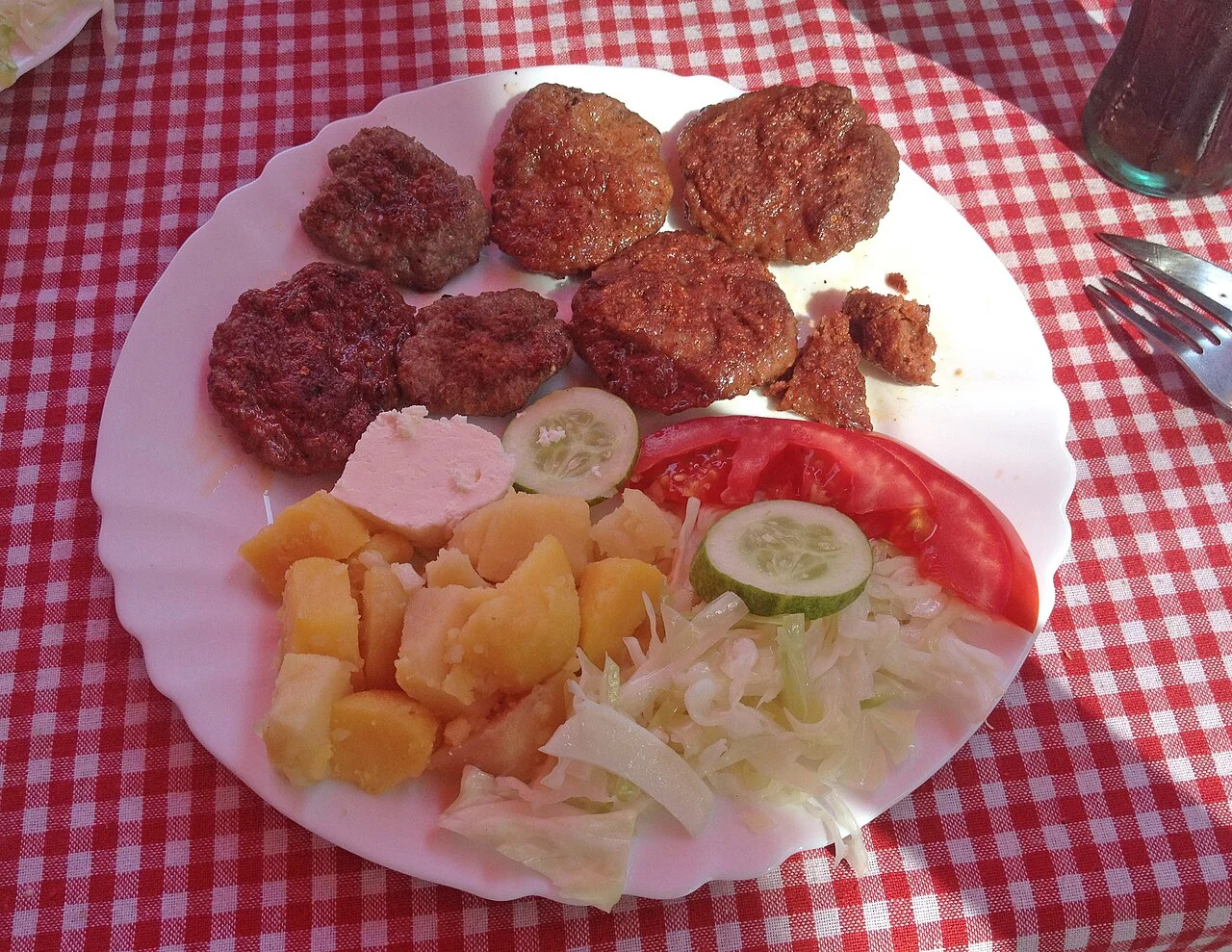 Priştine’de Te Martini’de kaydedilen qebapa tabağı, peynir, patates ve sebzeler; Ağustos 2015 tarihli servis örneği, güncel işletme veya menü önerisi değildir.