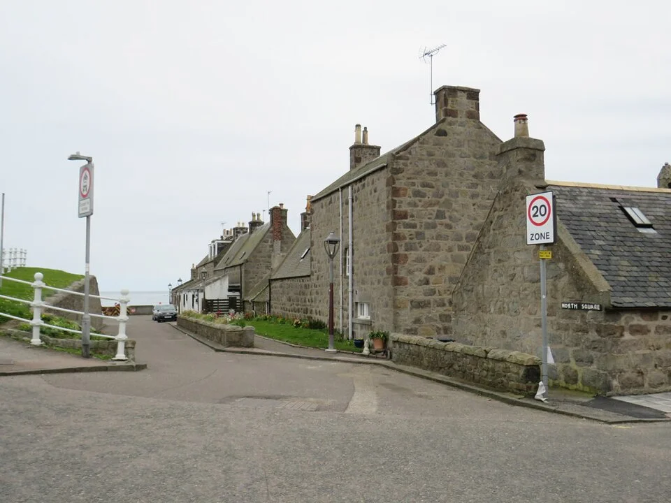 Quiet street between stone cottages in the residential Footdee neighbourhood, Aberdeen; April 2023.