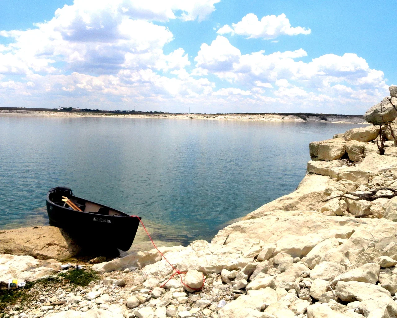 Canoe tied beside the rocky Amistad shore, NPS archive