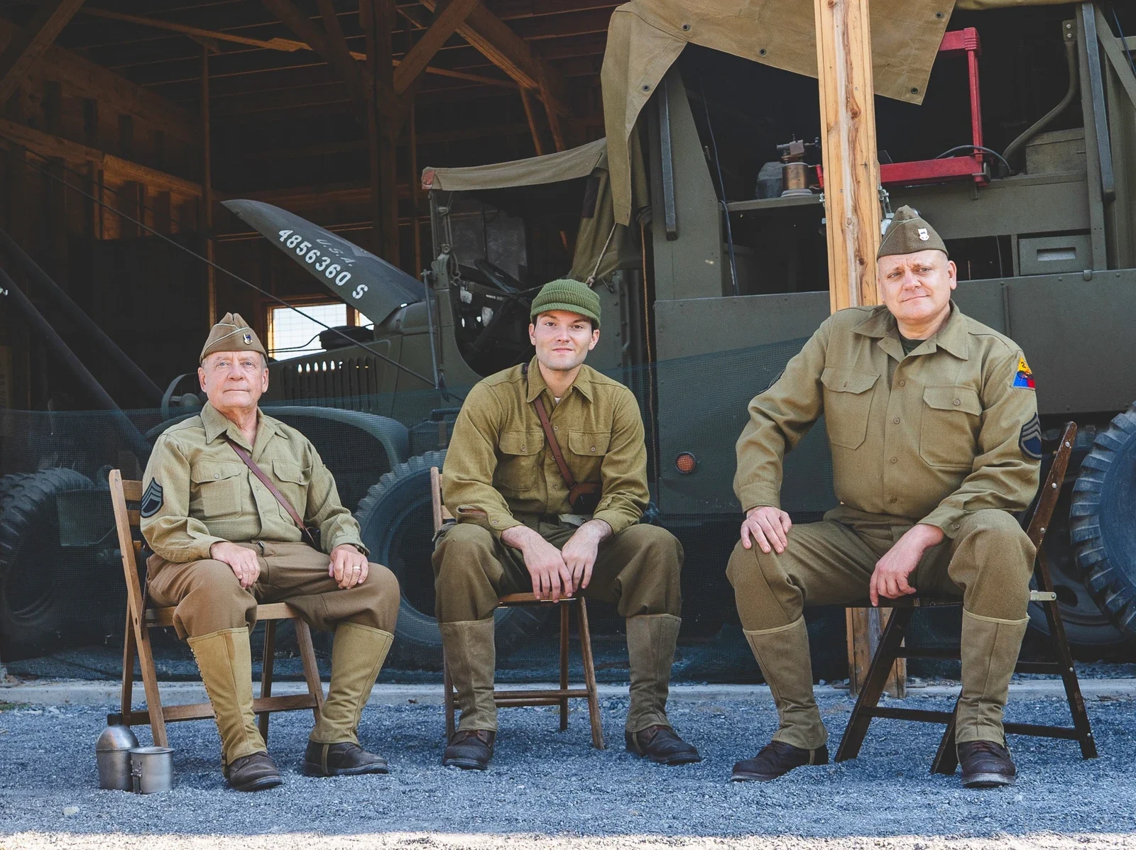 Three reenactors seated in front of a historic vehicle at Carlisle Army Expo 2025