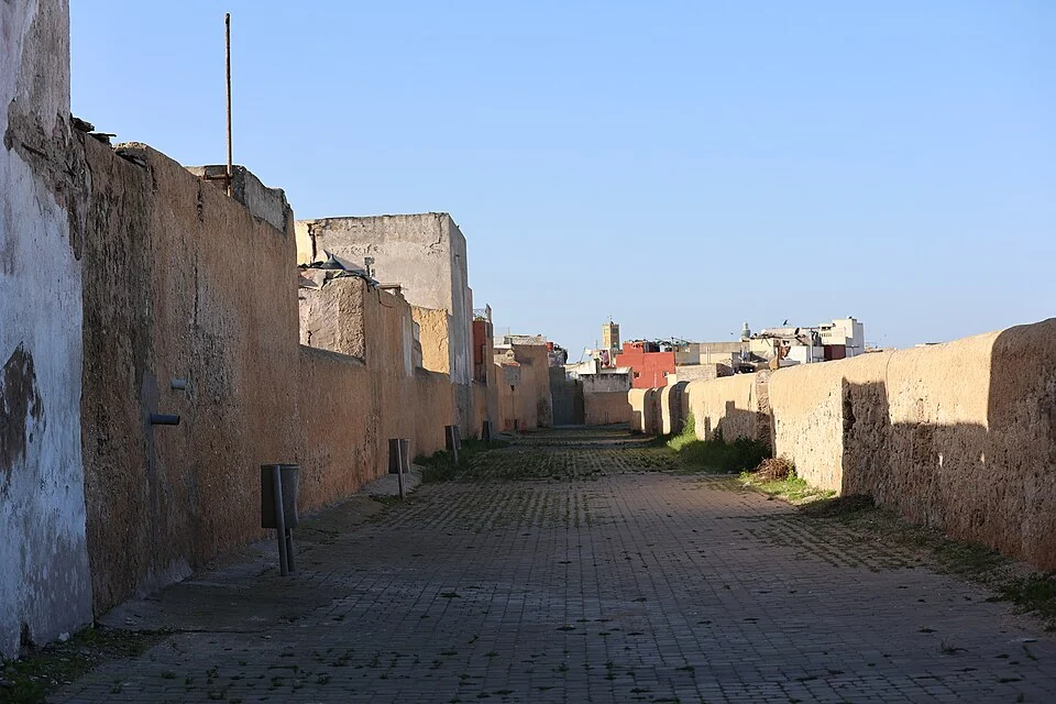Mazagan surları boyunca taş döşeli yol ve uzaktaki kent silueti, 23 Kasım 2024. Fotoğrafçı: Reda benkhadra; bugünkü geçiş koşullarını göstermez.