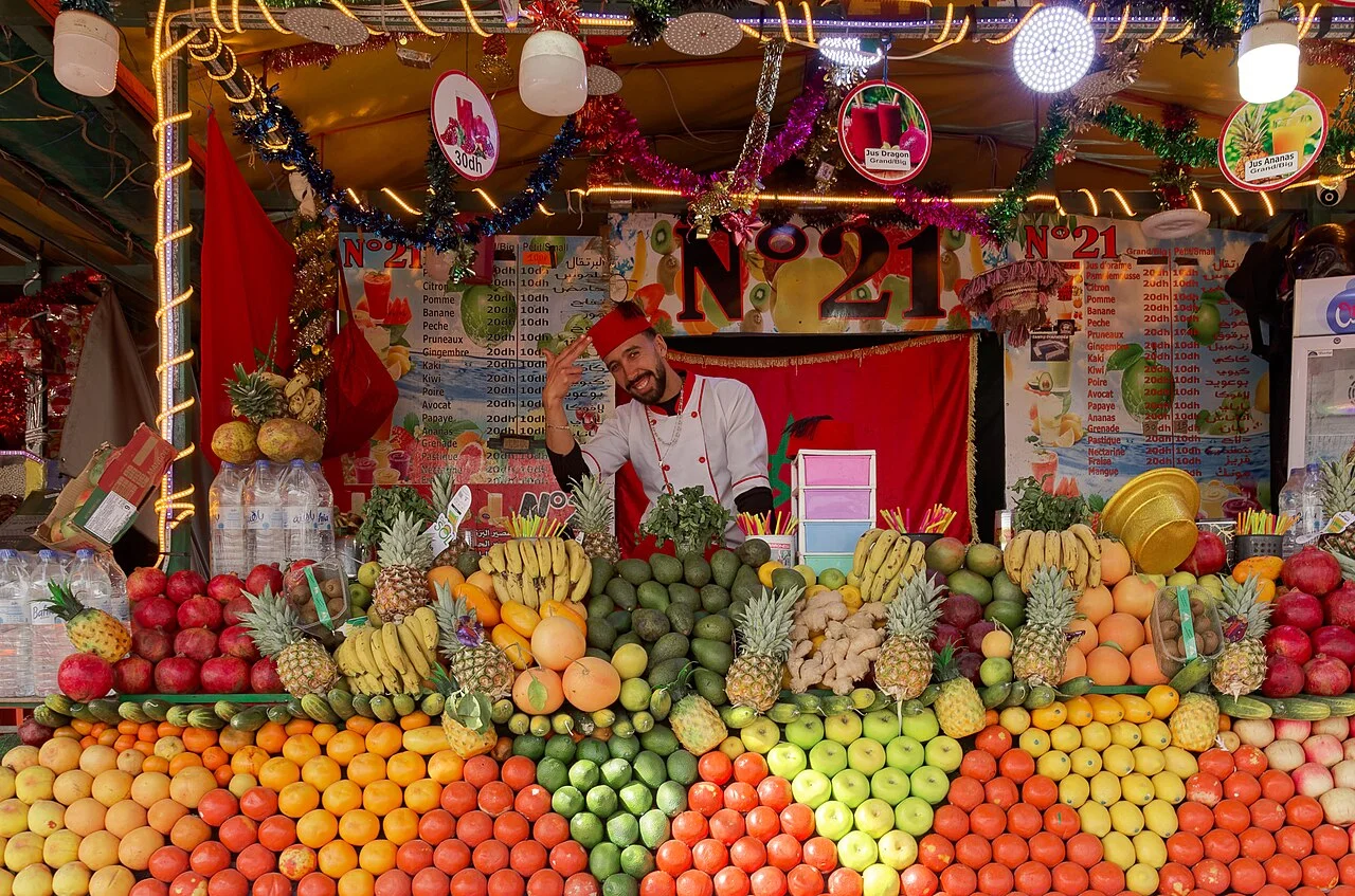 Fruit and juice stall at Jemaa el-Fna in Marrakech, January 2025; people appear in city context, without product or Tatilmerkezi endorsement.