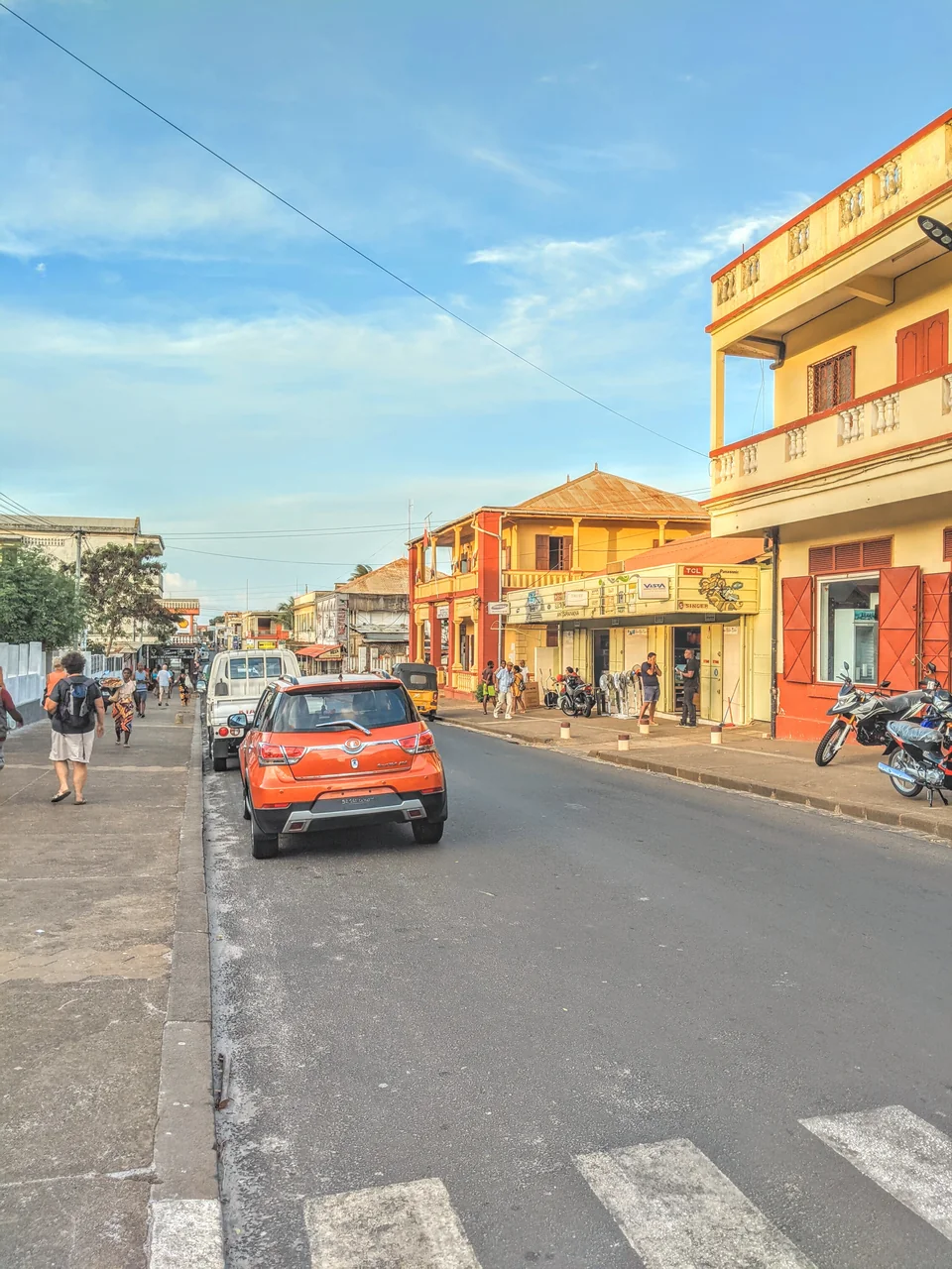 Orange car beside the pavement and colourful buildings on Rue Colbert