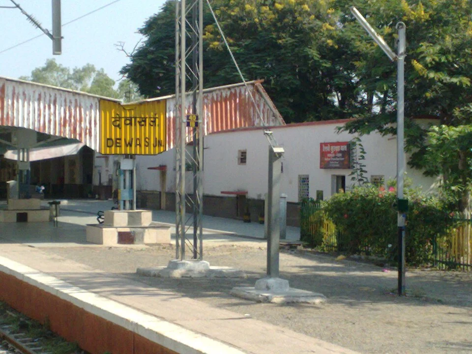 Dewas Junction istasyonunun sarı ad tabelası, peron kenarı ve yapıları, 4 Kasım 2012. Fotoğrafçı: Superfast1111; güncel tren tarifesi veya peron düzeni değildir.