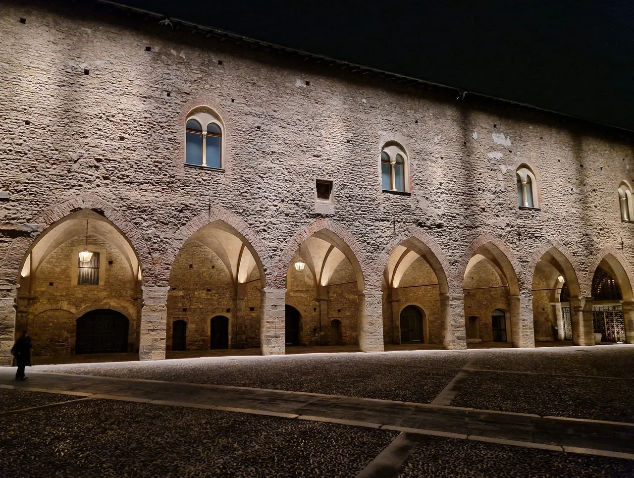 Illuminated stone arches and facade around Piazza Vecchia in Bergamo at night, October 2025
