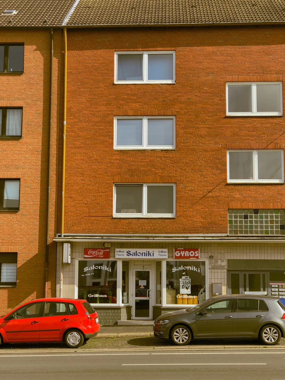 A brick residential building, street and parked cars in Bochum