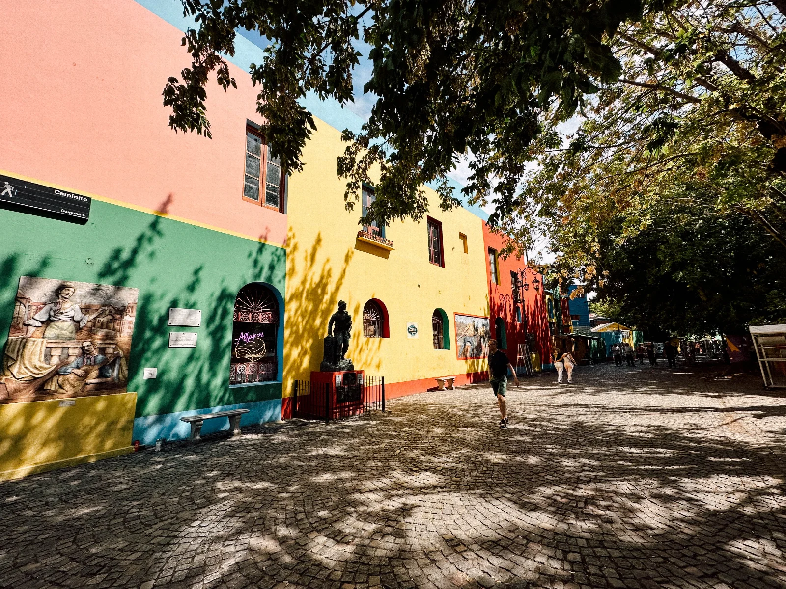 Colourful façades, cobblestones and tree shadows along Caminito in Buenos Aires
