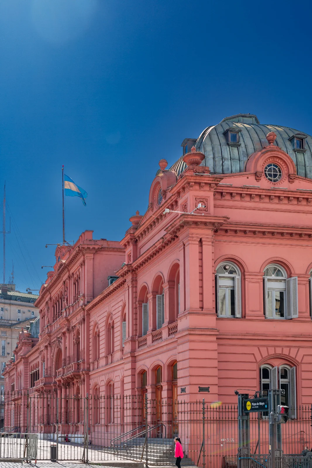 The pink façade and dome of Casa Rosada in Buenos Aires, with the Argentine flag against a blue sky