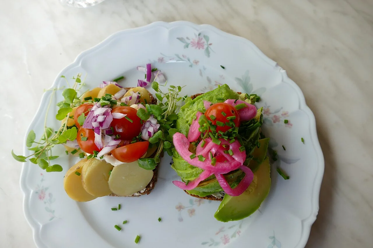 Kopenhag’da avokado ve patates üst malzemeli smørrebrød; 21 Ağustos 2022 tarihli gerçek yemek fotoğrafı.