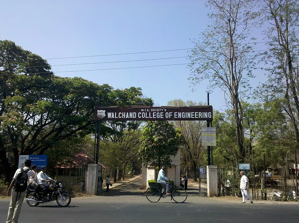 Named Walchand College entrance in Sangli with road, cyclist and trees