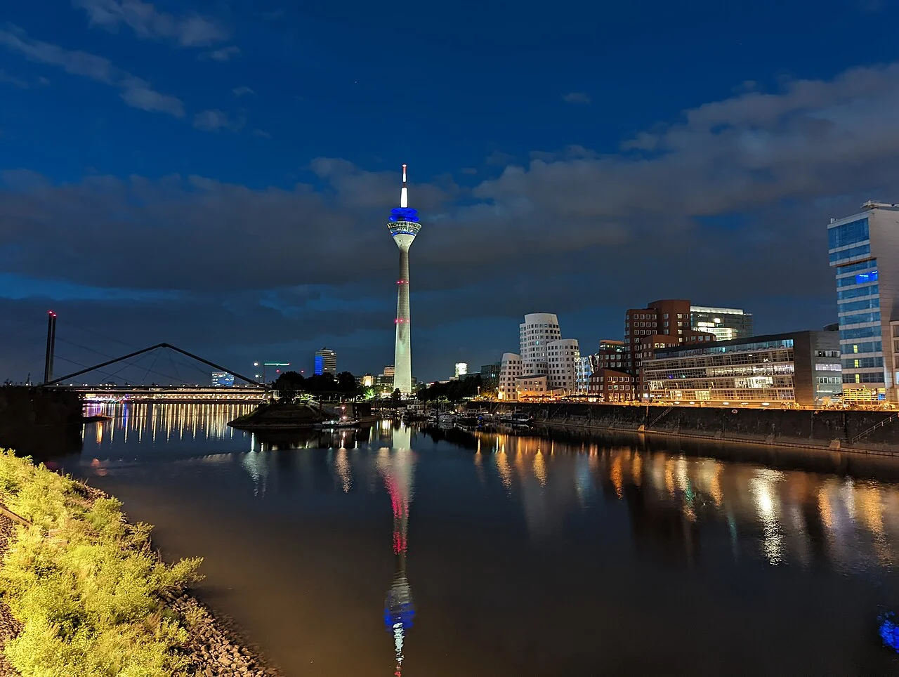 Düsseldorf MedienHafen çevresinde gece ışıkları ve Ren üzerindeki yansımalar; Haziran 2022 fotoğrafı.