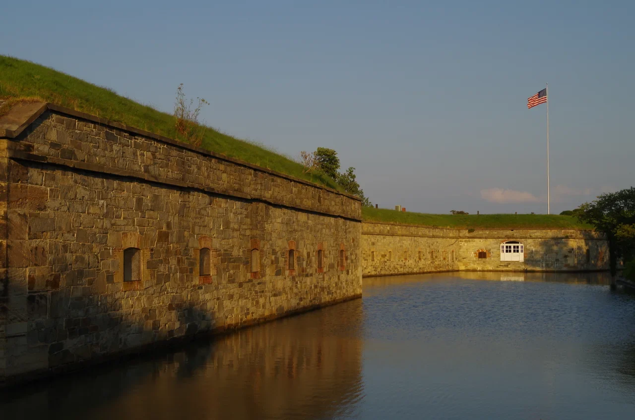 Stone walls of Fort Monroe reflected in its moat at twilight, NPS archive
