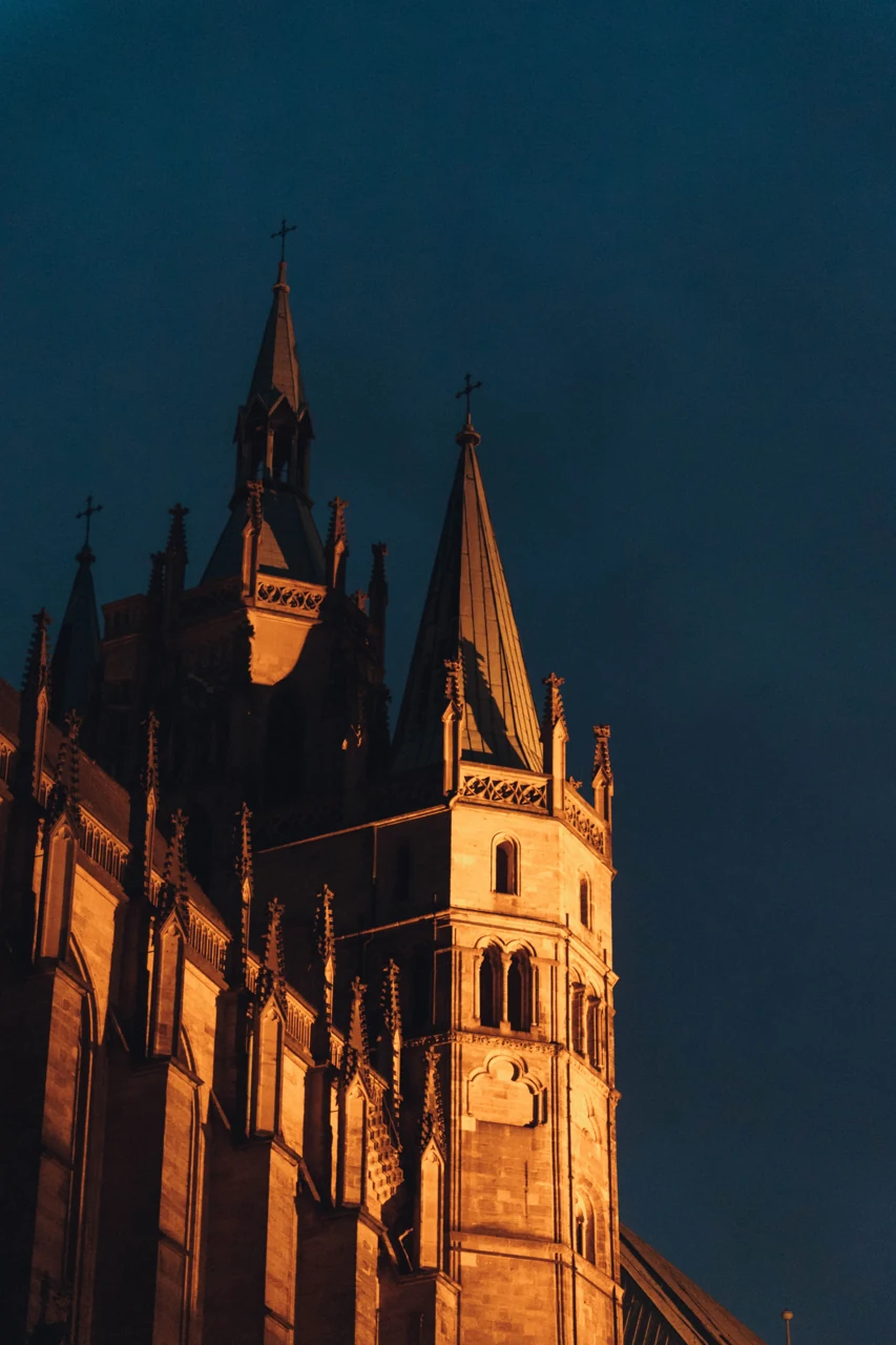 Domberg üzerindeki aydınlatılmış bir kilise kulesinin yakın gece kadrajı.