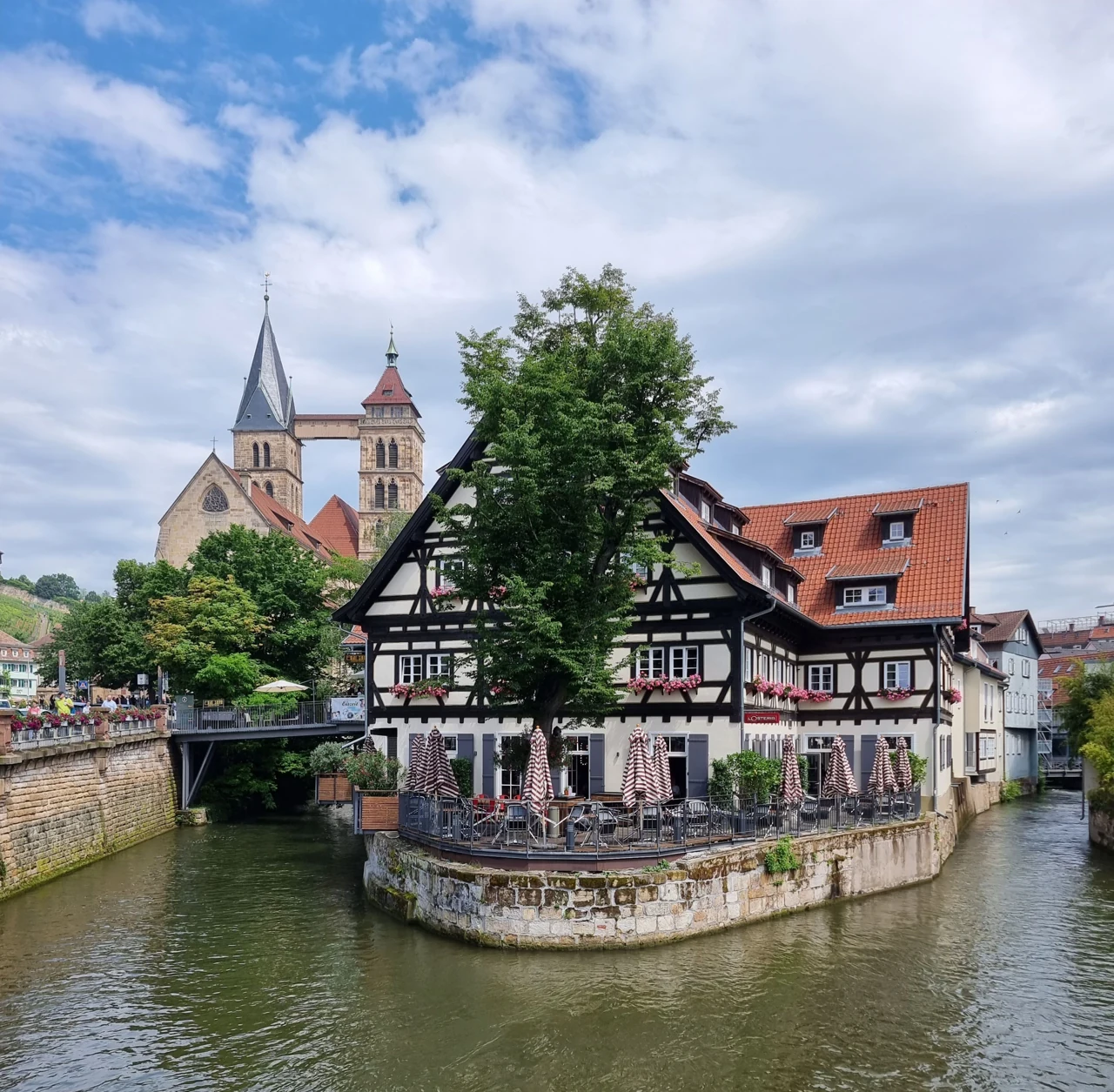 Historic buildings by an Esslingen channel with St Dionys towers behind
