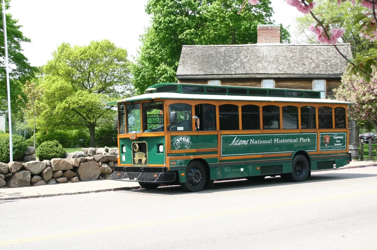 Archival park trolley dropping visitors at the Adams birthplaces; not a current service promise