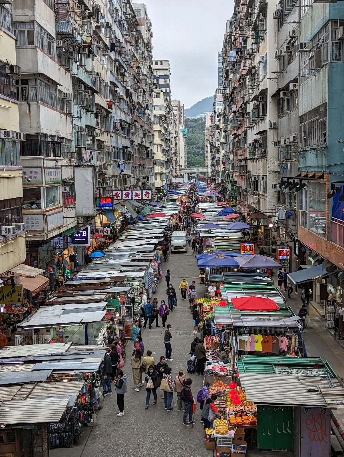 Hong Kong sokak pazarı tezgâhları; yemek yürüyüşü için gerçek şehir bağlamı, wonton tabağı veya adı verilen restoran değildir.