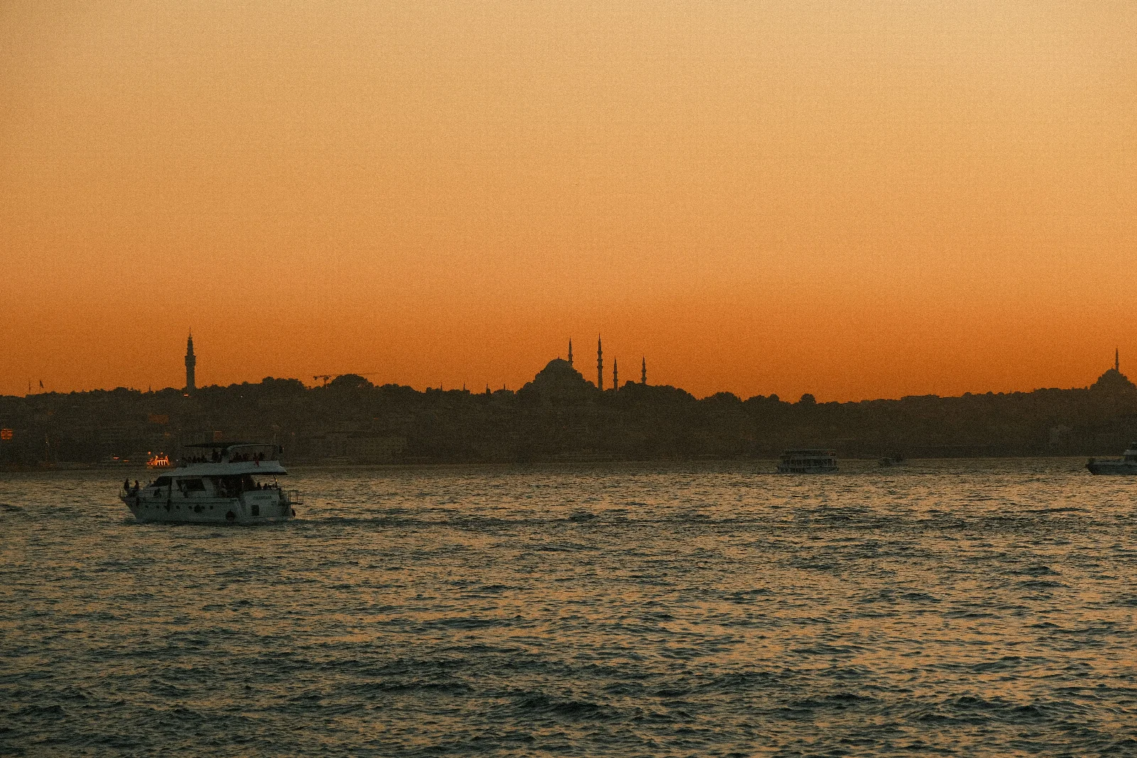 Istanbul’s domed skyline, orange sunset sky and boats on the water