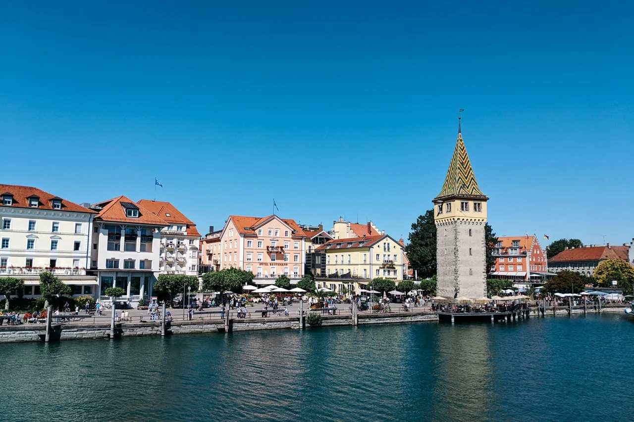 A wider Lindau harbour view with waterfront buildings and Mangturm