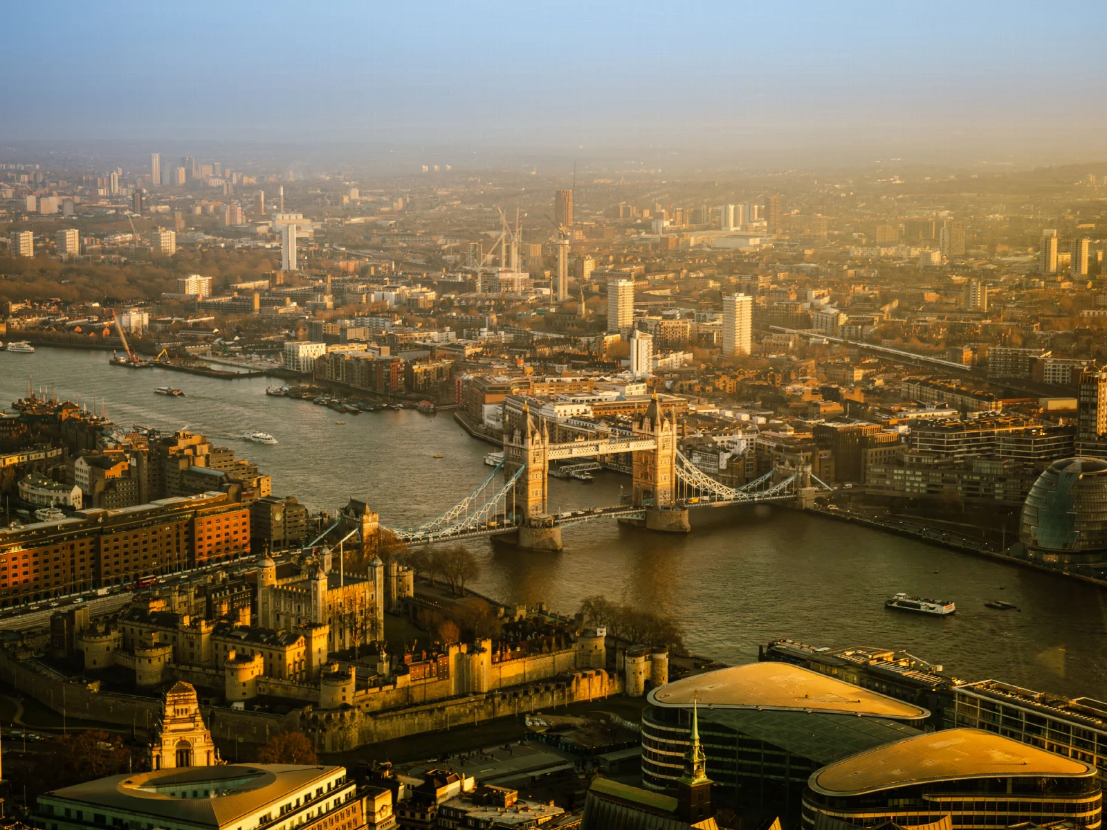 An elevated view of Tower Bridge, the River Thames and London’s cityscape in warm evening light
