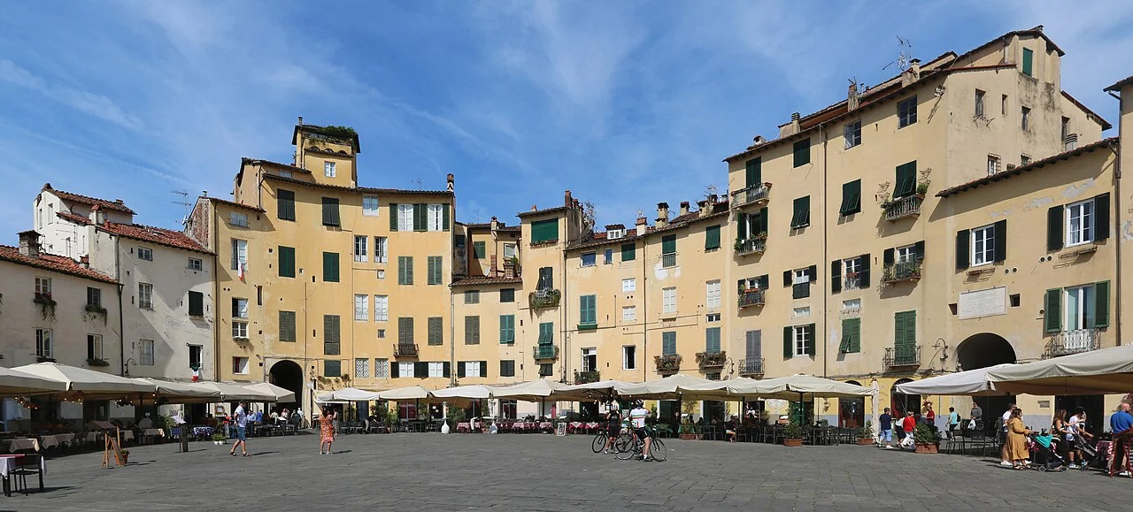 Lucca Piazza dell’Anfiteatro meydanında kıvrımlı ev sırası ve kafeler; Eylül 2021 fotoğrafı.