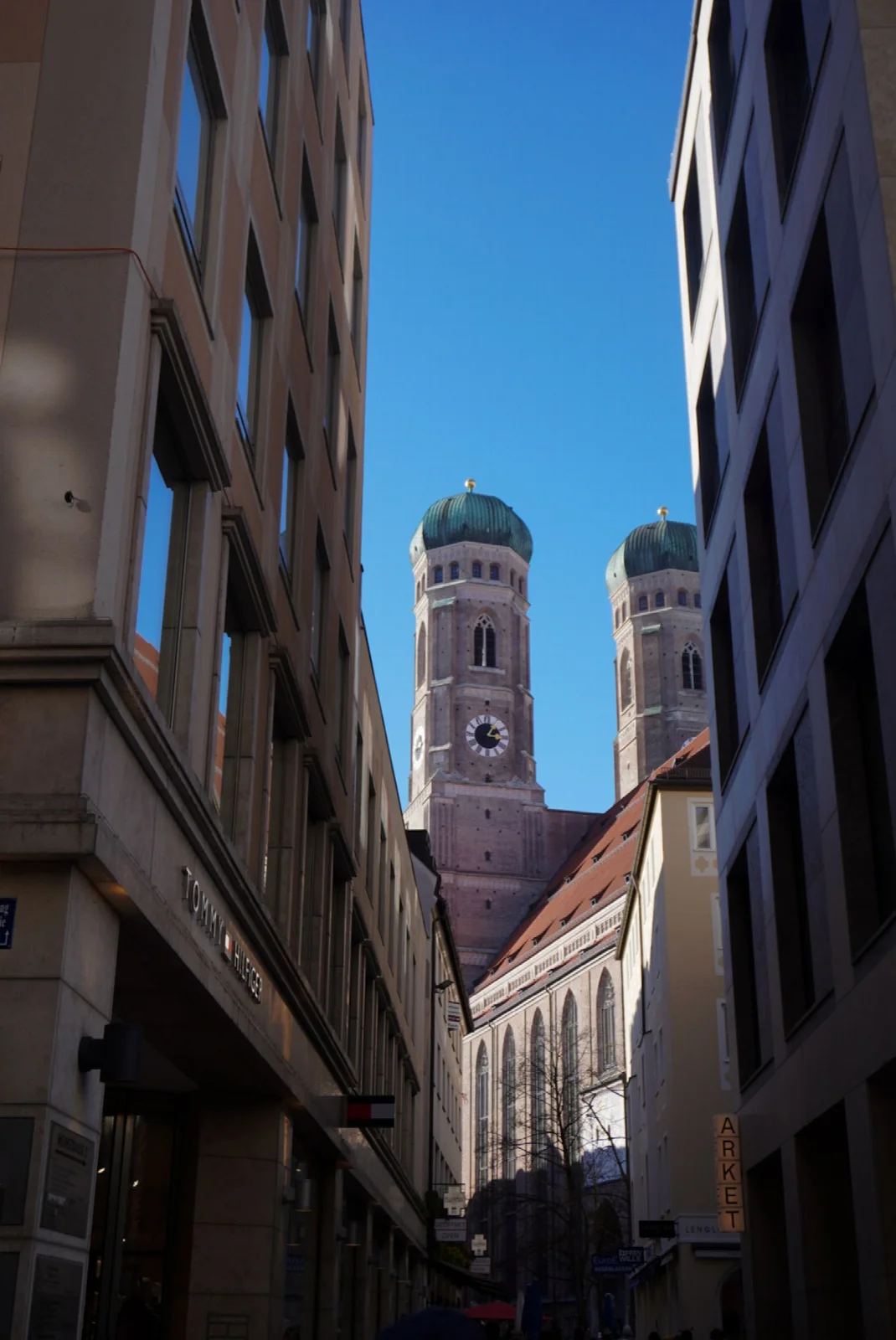 A view towards the Frauenkirche towers between buildings on a Munich street