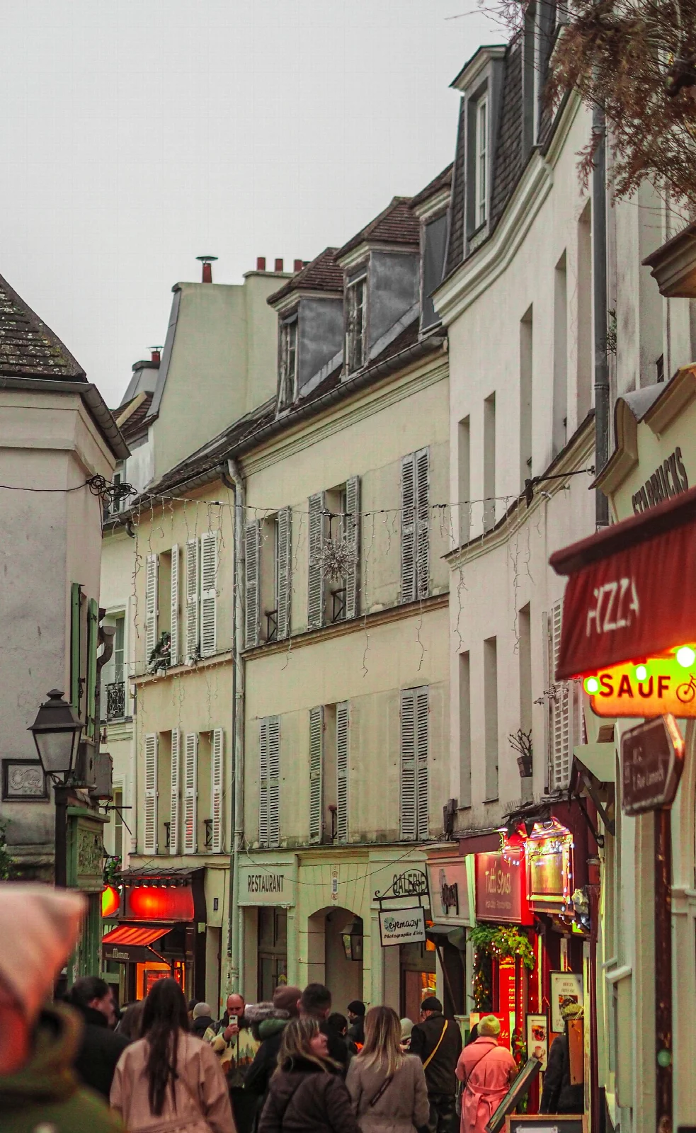 A lively neighbourhood street between historic buildings in Montmartre, Paris