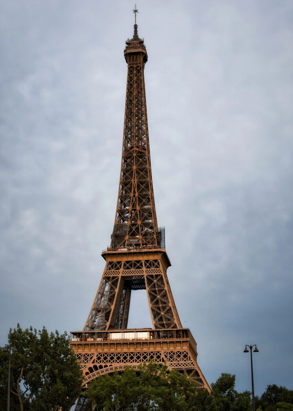 The iron structure of the Eiffel Tower beneath a cloudy sky in Paris