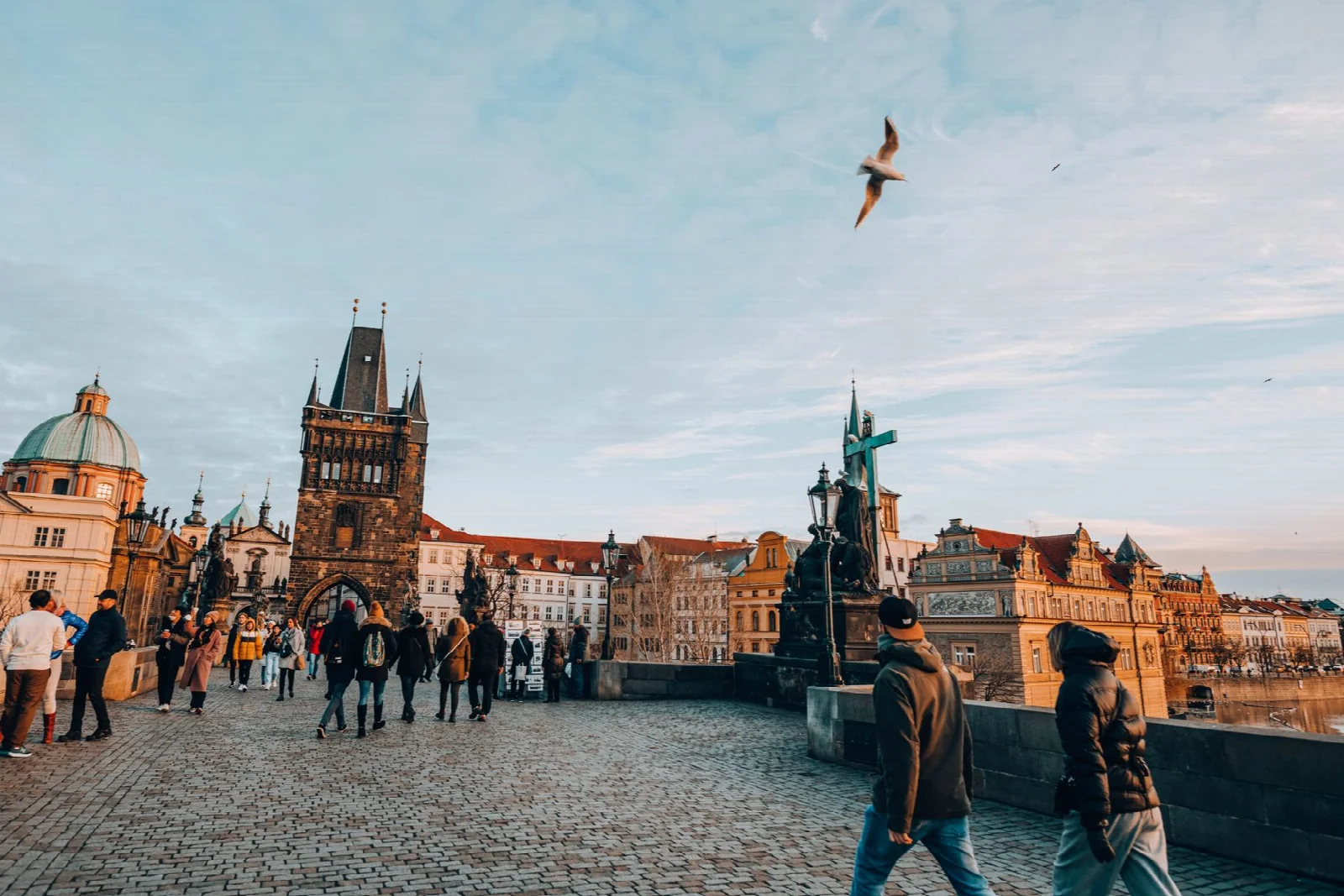 Visitors walking on Prague’s Charles Bridge with the Gothic bridge tower beyond
