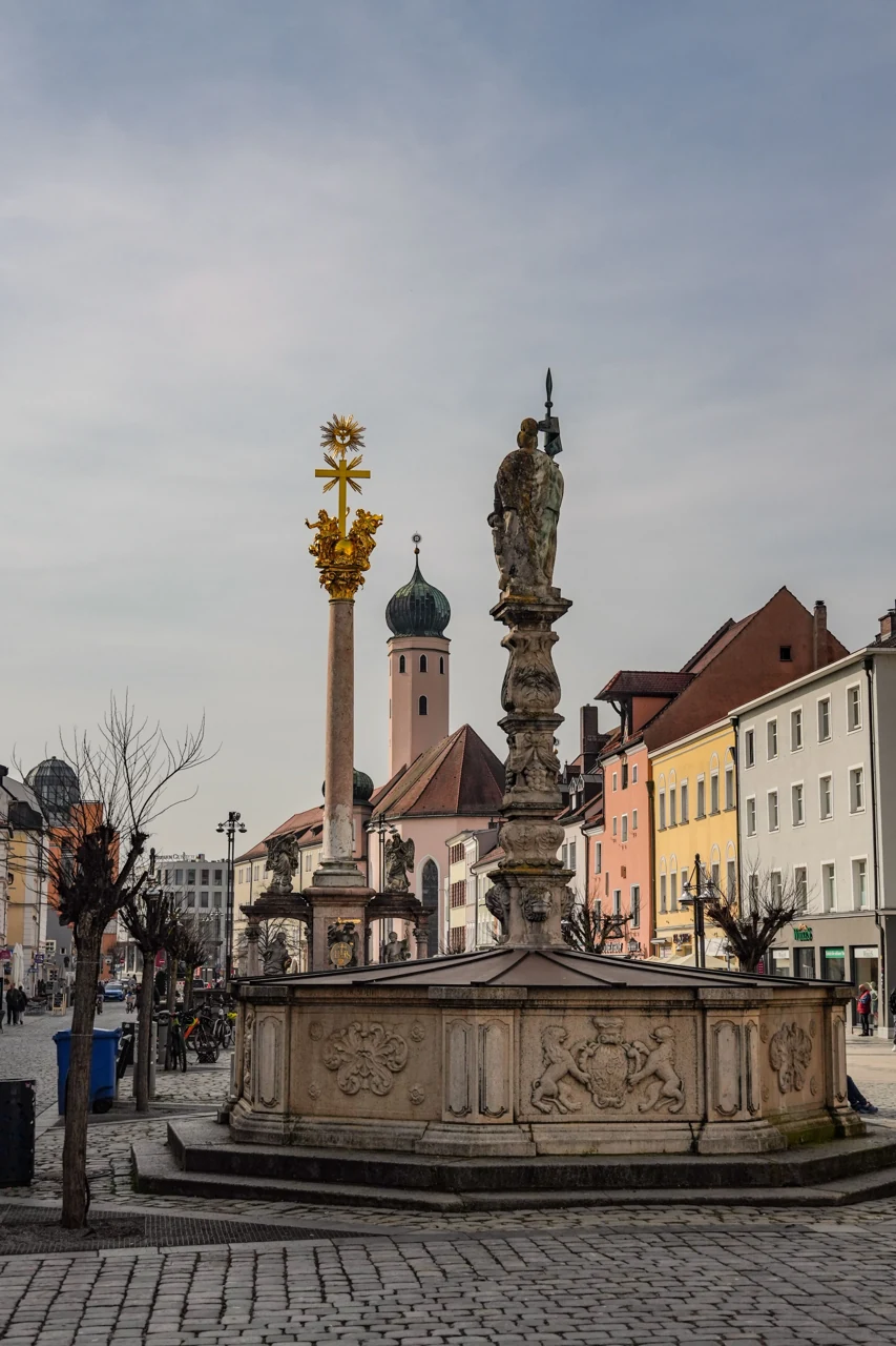 Rosenheim meydanındaki çeşme ve arkada St. Nikolaus Kilisesi