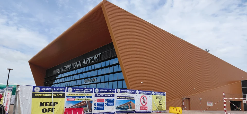 Orange facade of Tamale International Airport terminal with construction safety barriers in front