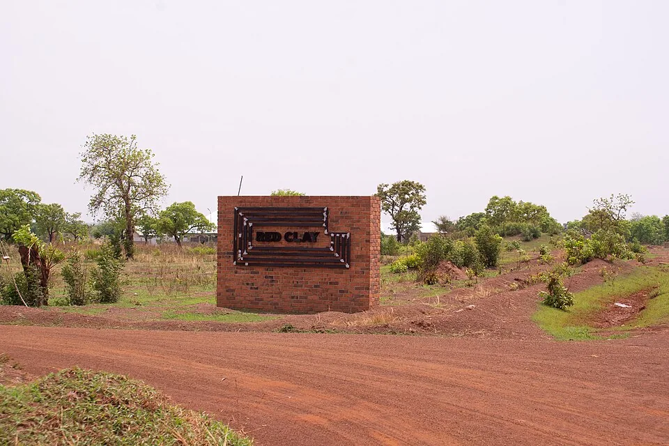 Brick entrance sign at Red Clay, red dirt track and vegetation