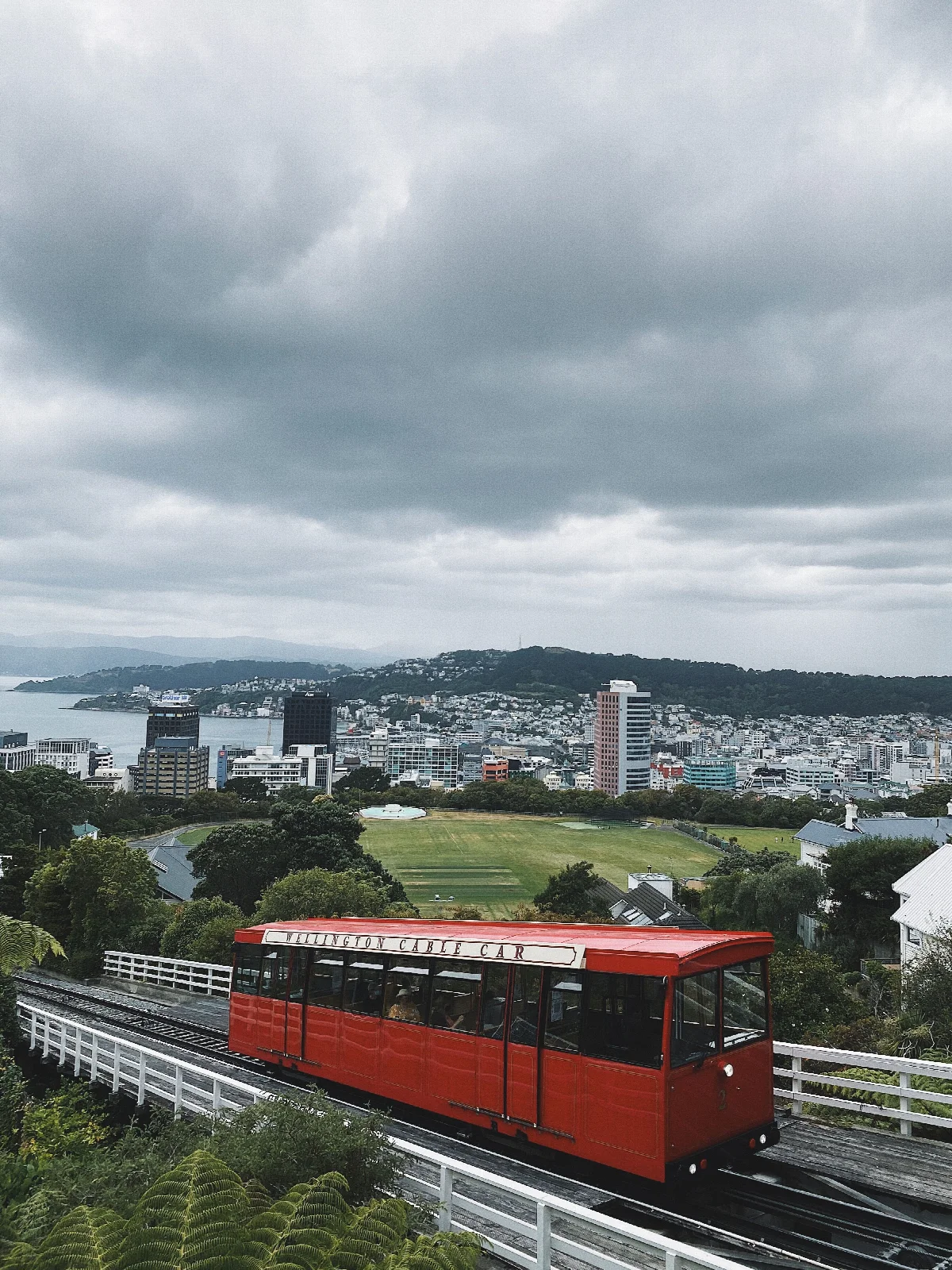 The red Wellington Cable Car funicular, sloping tracks and a city view from Kelburn behind it